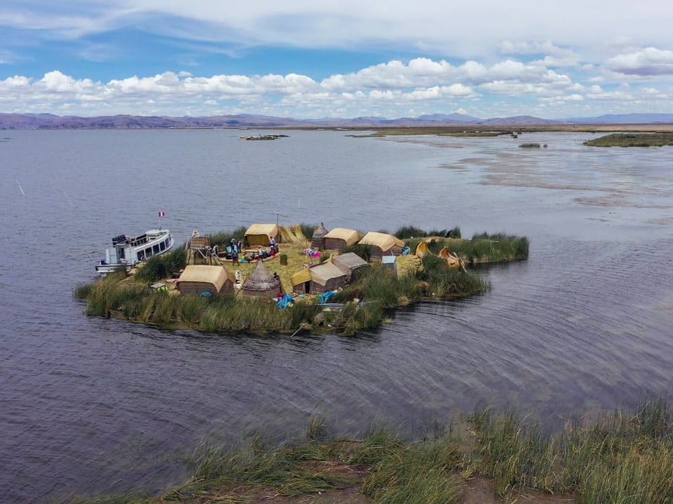 Schwimmendes Inseldorf mit Hütten auf einem See.