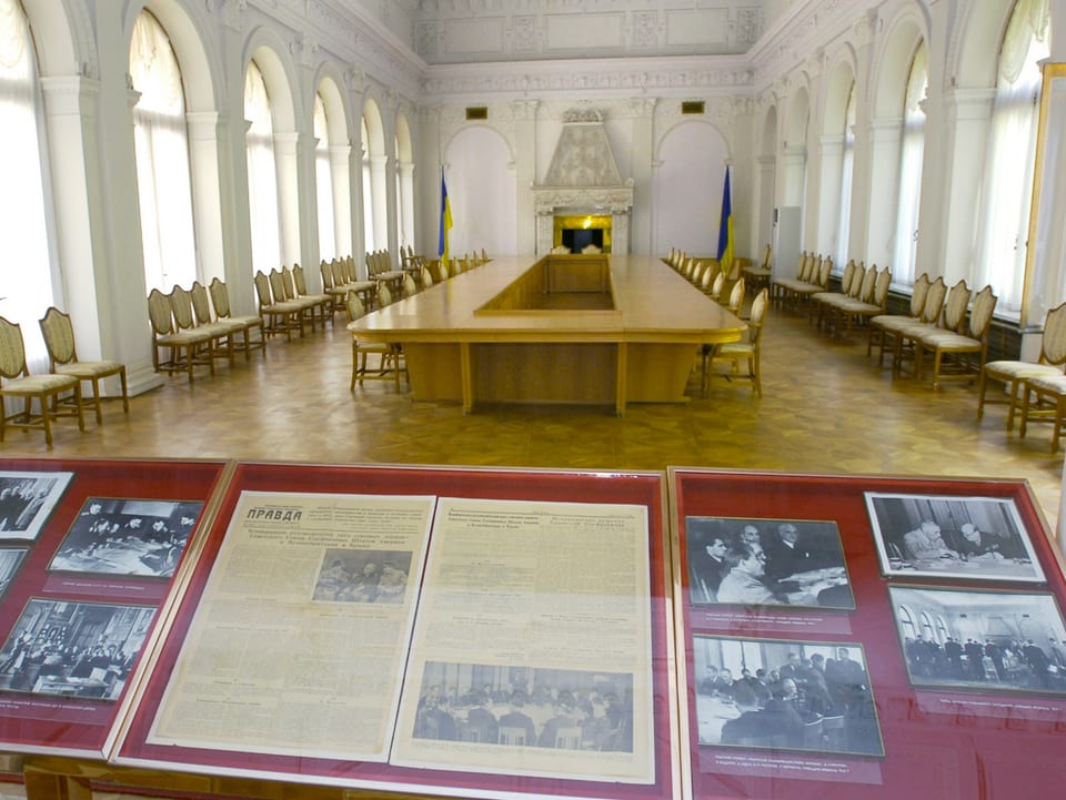 Schwarz-Weiss-Bilder des Treffens 1945 sowie damalige Zeitungsausschnitte in mehreren goldenen Bilderrahmen, ausgestellt im Palast. 