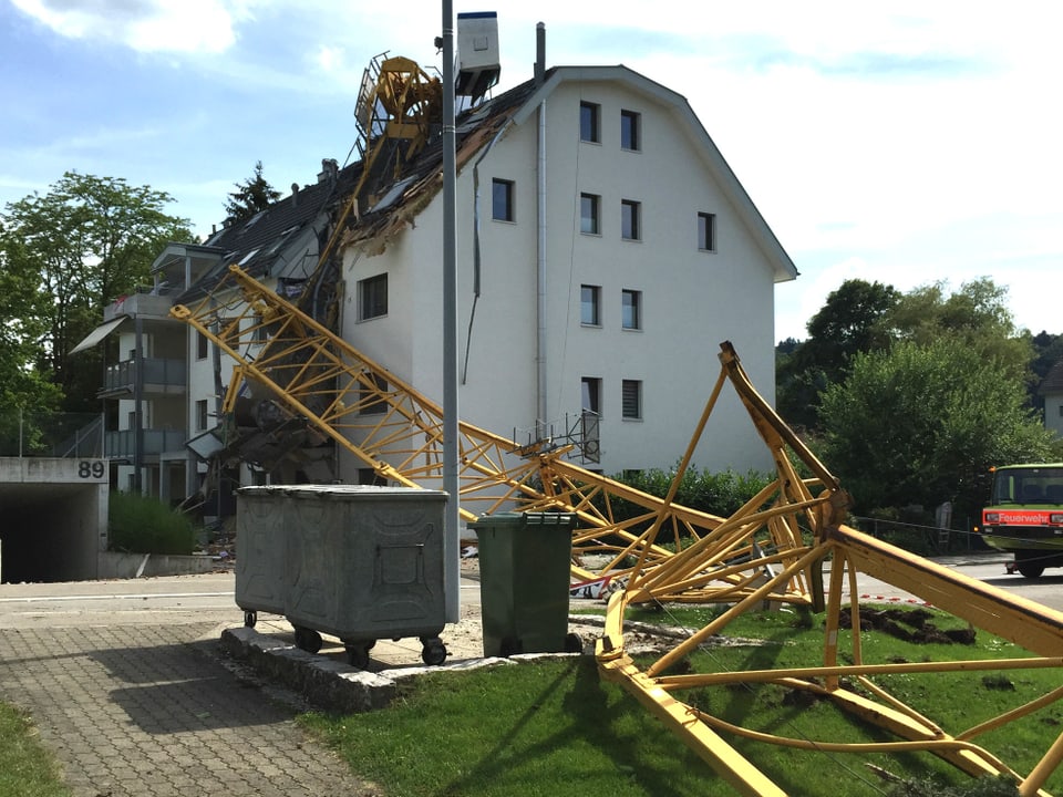 Ein zerbrochener Kran liegt auf einem Hausdach und auf der Strasse.