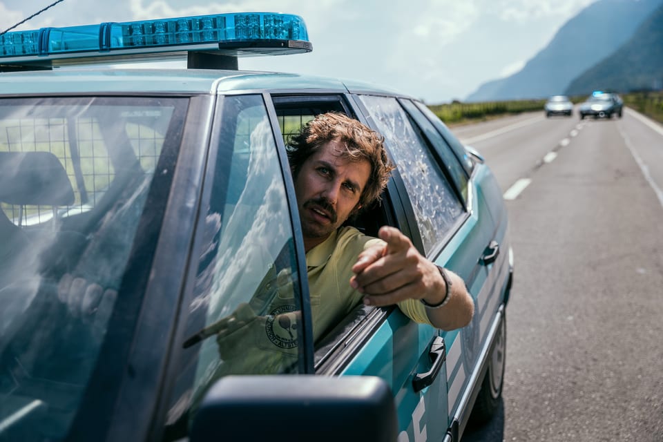 David Constantin alias Bax lehnt sich aus dem Fenster des Polizeiautos.