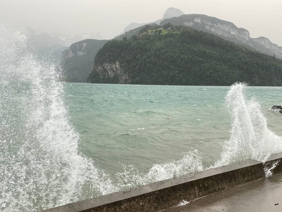 Wellen brechen sich an der Ufermauer. 