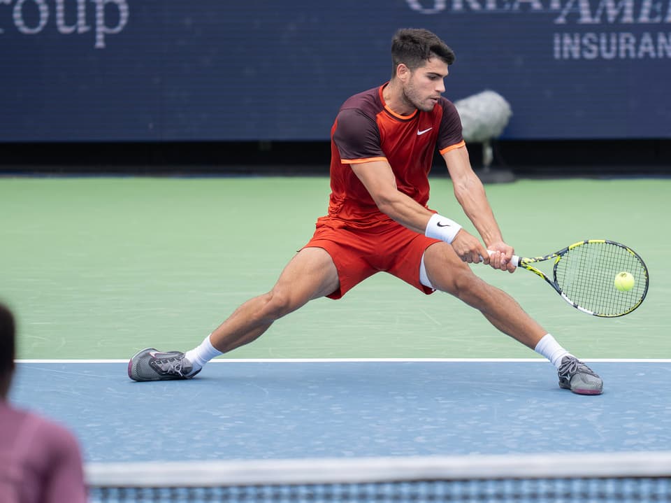 Tennisspieler in rotem Outfit, der einen Ball schlägt