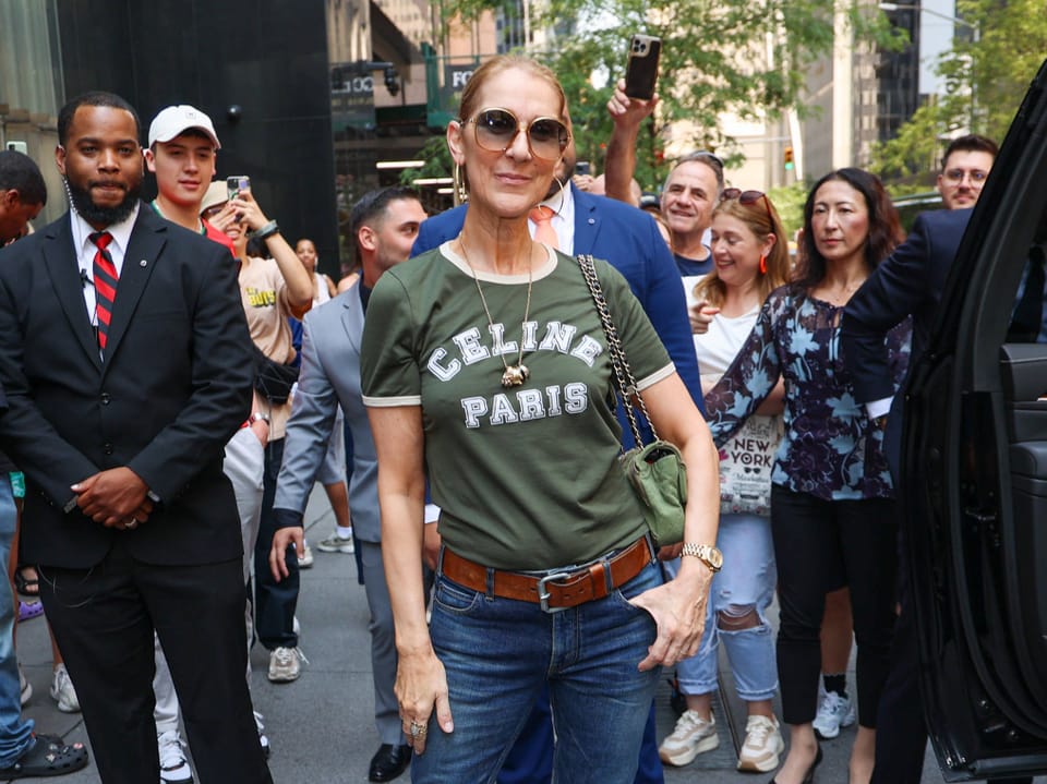 Frau in Celine-Paris-T-Shirt und Sonnenbrille von Menschen umgeben auf Strasse.