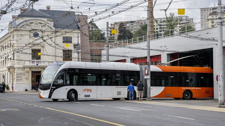 Zwei Busse an einer Haltestelle in einer Stadt.