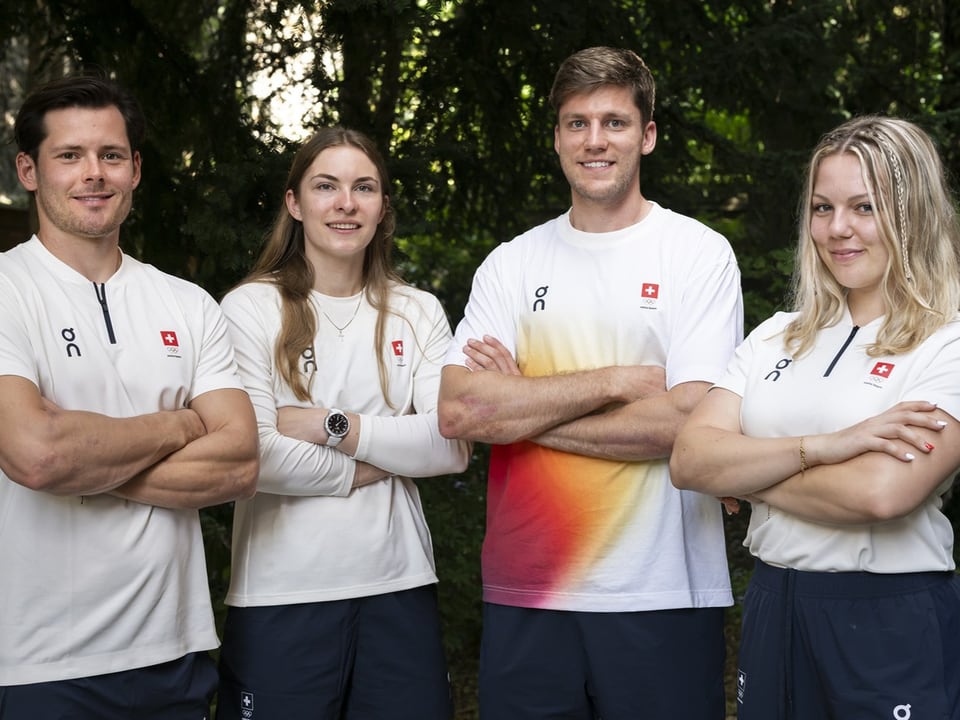 Vier Personen in Sportkleidung, die mit verschränkten Armen lächeln.