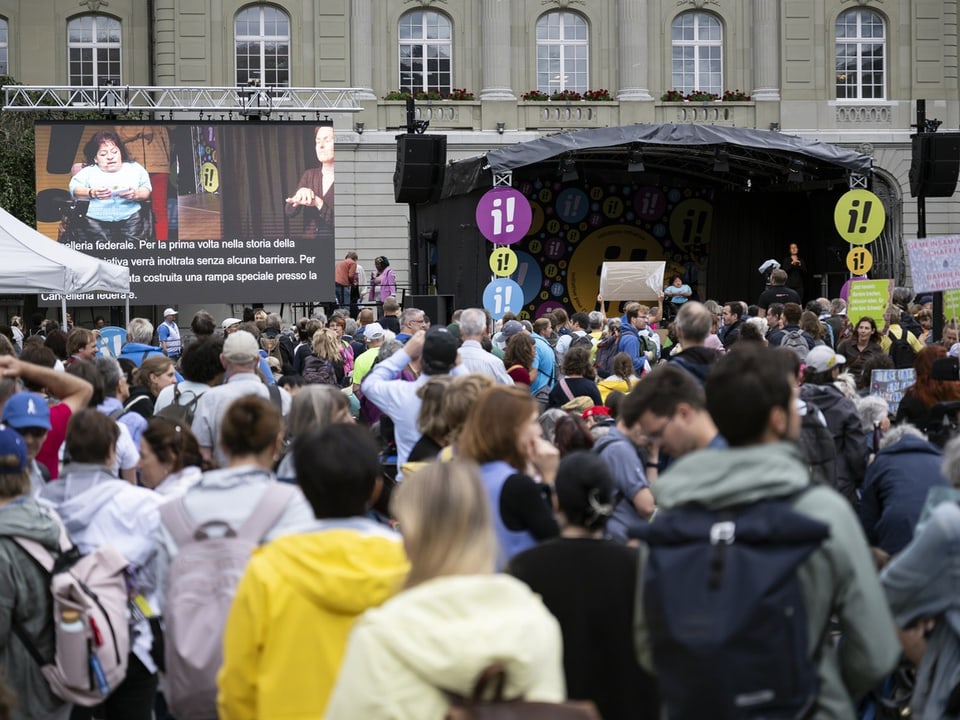 Menschenmenge versammelt vor einer Bühne bei einer Veranstaltung im Freien.