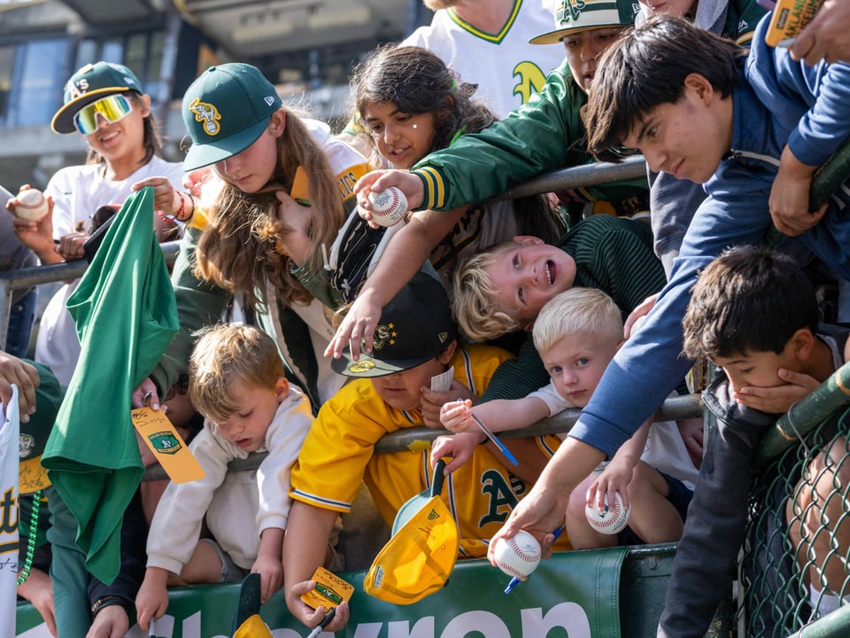 Kinder sammeln Autogramme bei einem Baseballspiel.