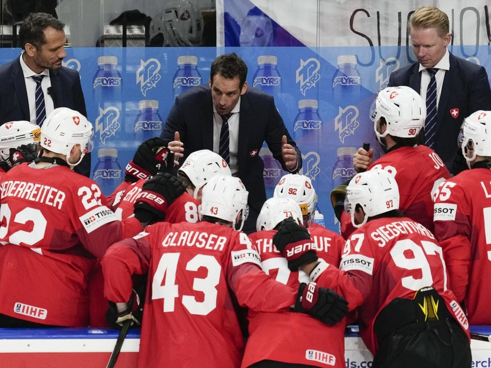 Eishockeytrainer gibt Anweisungen an das Team in roten Trikots.