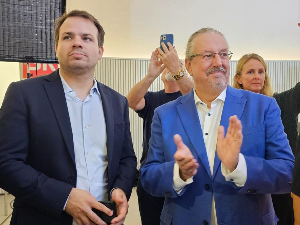 Zwei Männer in Anzügen applaudieren. 