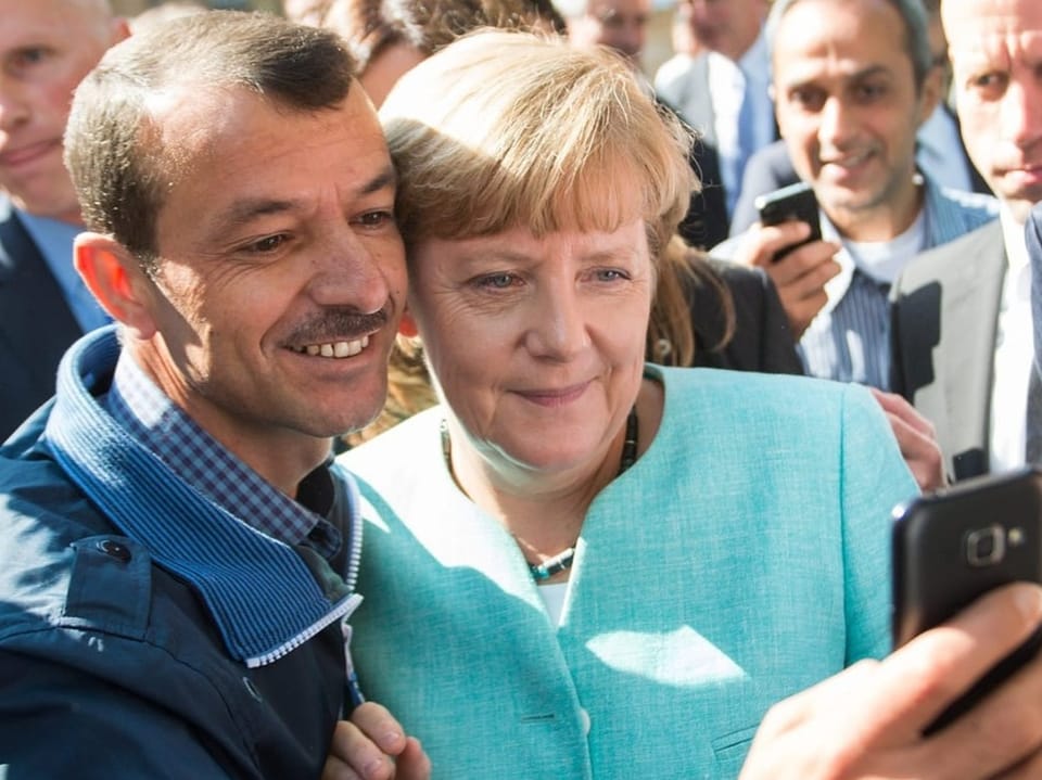 Ein Flüchtling aus Syrien macht ein Selfie mit Angela Merkel