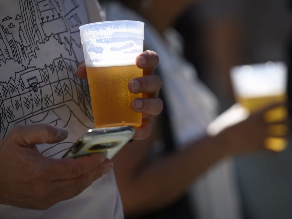 Zwei Personen und der Sonne am Biertrinken und eine Person hat noch ihr Smartphone in der Hand