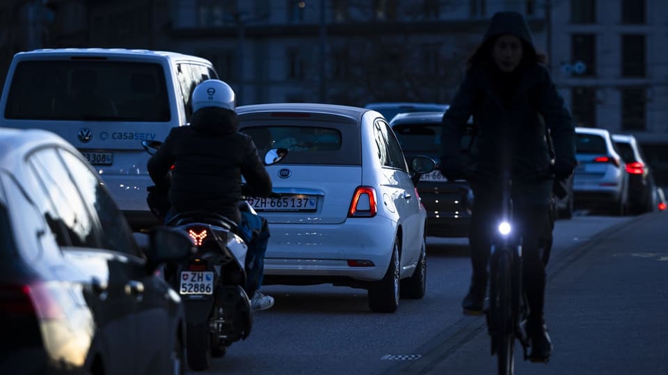 Autos stehen im Stau, rechts davon fährt ein Velo in entgegengesetzer Richtung.