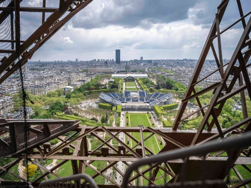 Blick durch den Eiffelturm auf Paris mit Wolken am Himmel.