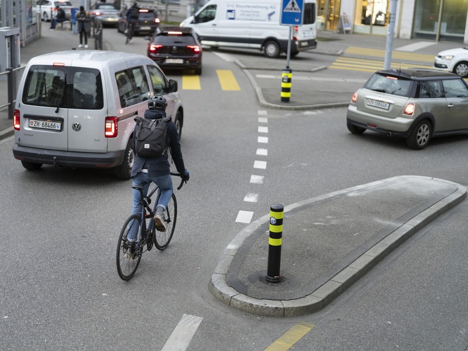 Aufnahme einer Zürcher Strasse – ein Velofahrer fährt an einer Verkehrsinsel vorbei.