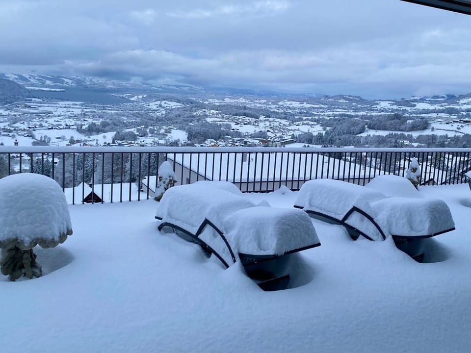 Verschneites Tal mit zugeschneiten Terrassenmöbeln.