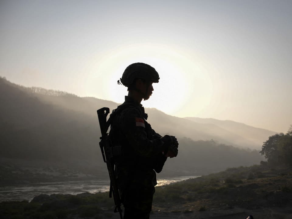 Silhouette eines Soldaten bei Sonnenuntergang in bergiger Landschaft.