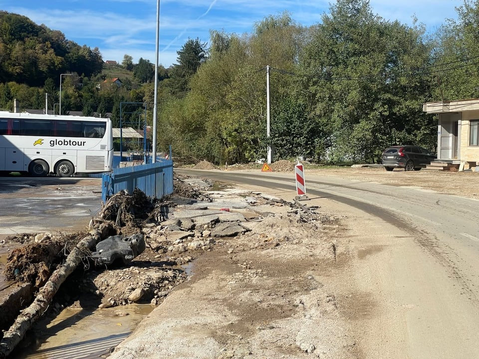 Unbefestigte Strasse mit Bauarbeiten und geparktem Bus.