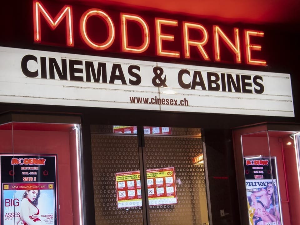 Kinoeingang mit Neonschriftzug 'MODERNE' und Schild 'CINEMAS & CABINES'.