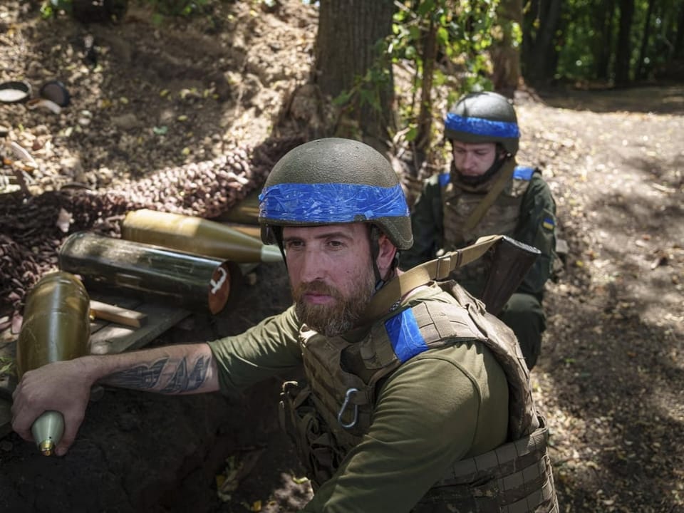 Zwei Soldaten mit blauen Helmen und Westen in einem Wald.