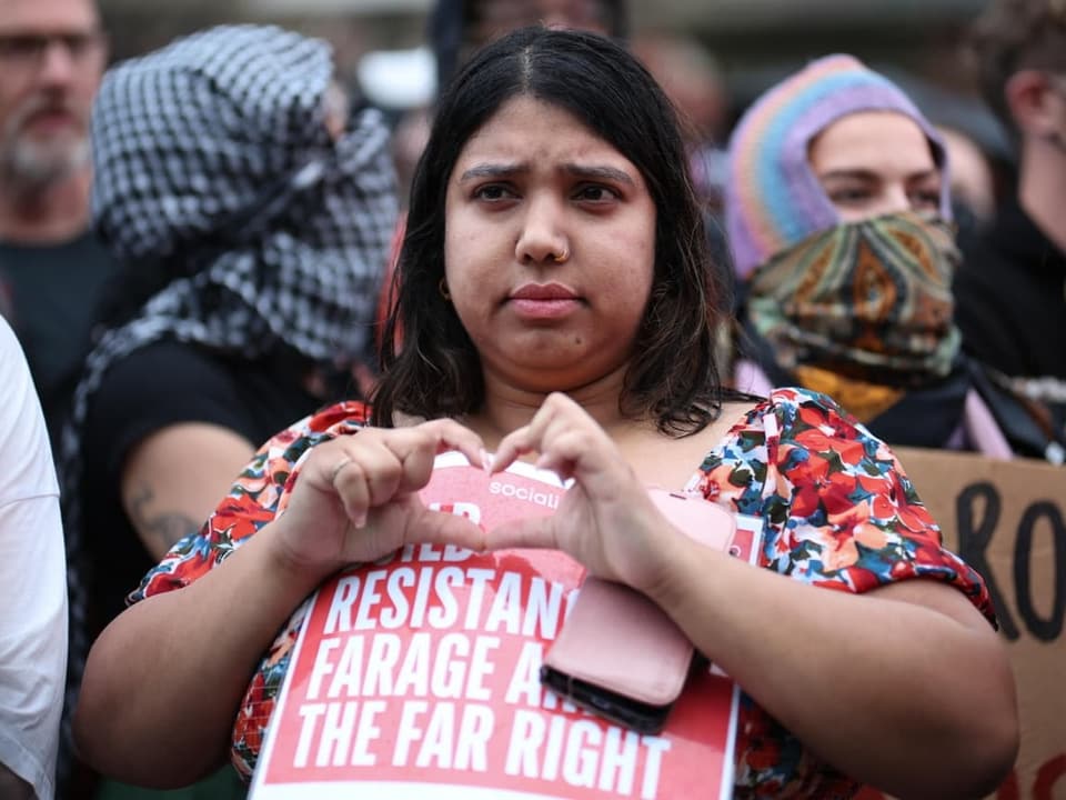 Eine Demonstrantin formt ein Herz mit den Fingern.