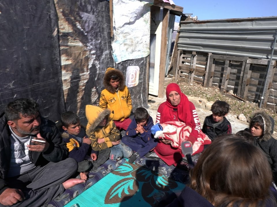 Syrische Flüchtlinge sitzen in einem Kreis. 