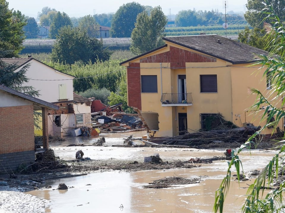 Überflutetes Haus mit Schlamm und Trümmern nach Hochwasser.