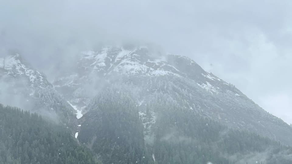 Vom Tal aus gesehen: Schneeflocken die an den Bergen entlang ziehen.