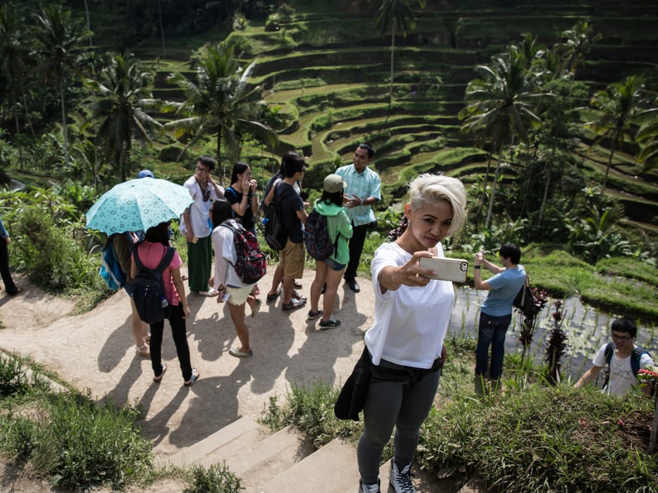 Touristin macht Selfie vor Reisterrassen mit Gruppe.