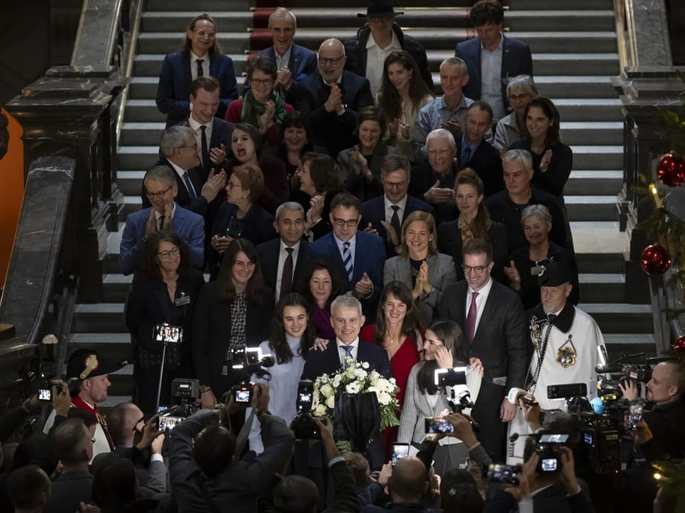 Beat Jans, umringt von Dutzenden Personen, auf den Treppen des Bundeshauses vor den Medien.