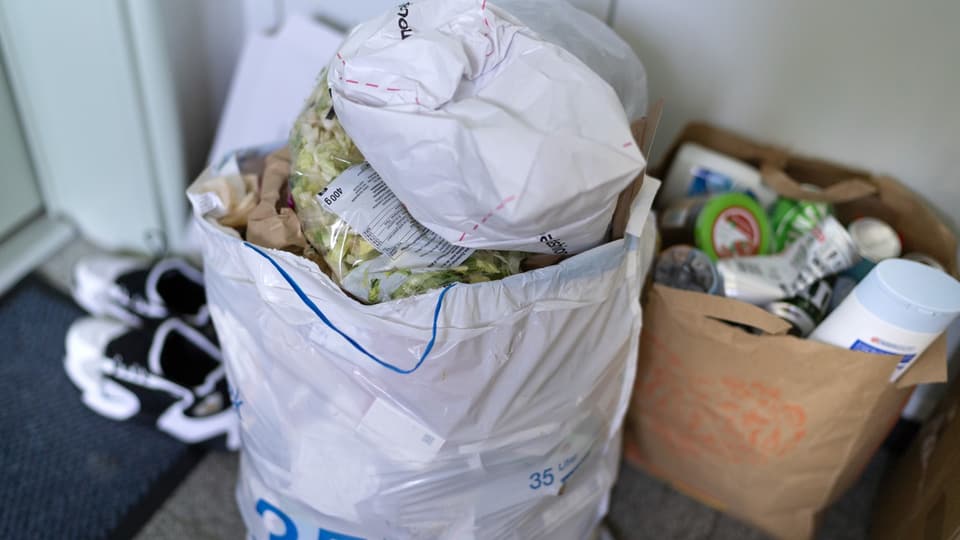 Kehricht-Sack mit einer ungeöffneten Salat-Packung.