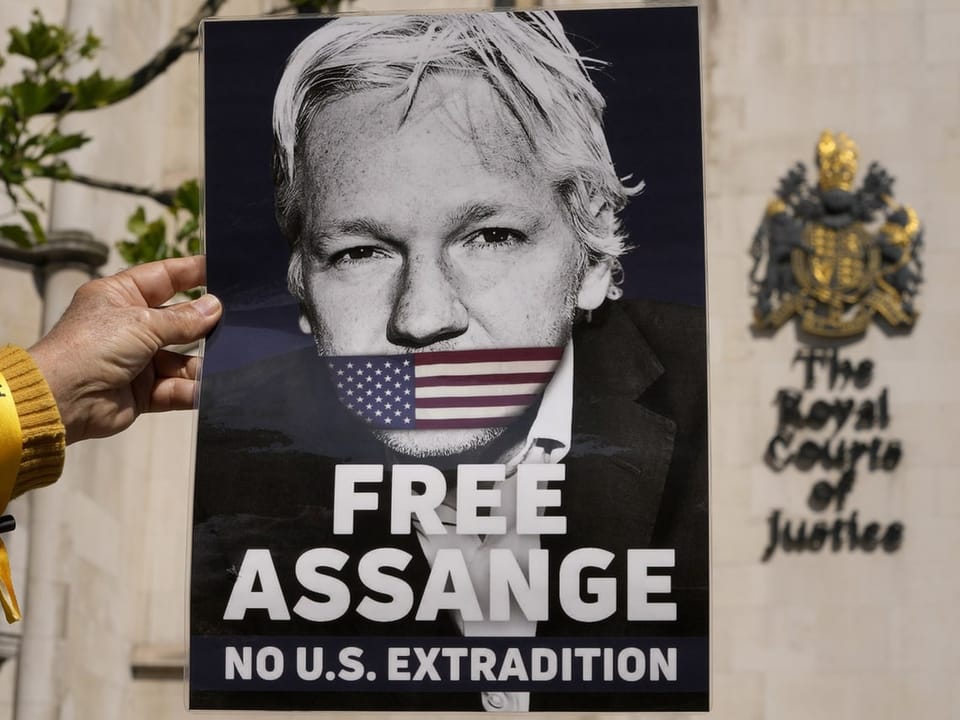 Hand hält Plakat mit Bild von Assange vor der Royal Courts of Justice.