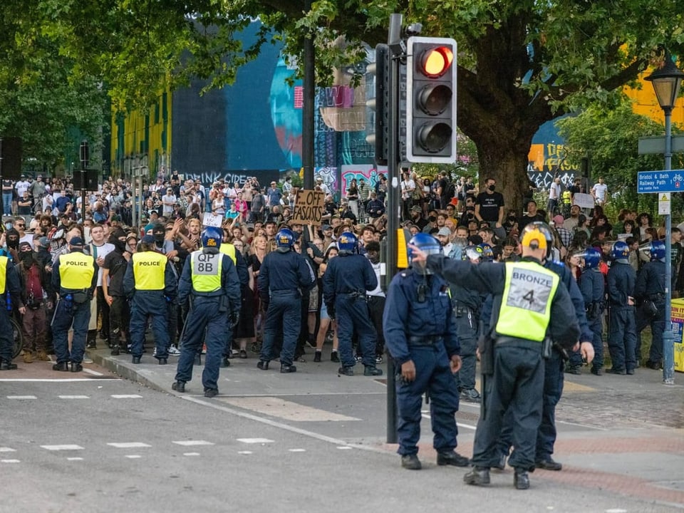 Polizisten stellen eine Linie, sodass die Demonstranten nicht durchkommen können.