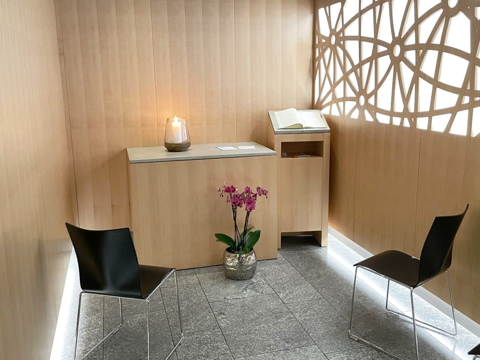 Gebetsraum der Flughafenkirche mit zwei Stühlen, Blumen, einer Kerze.