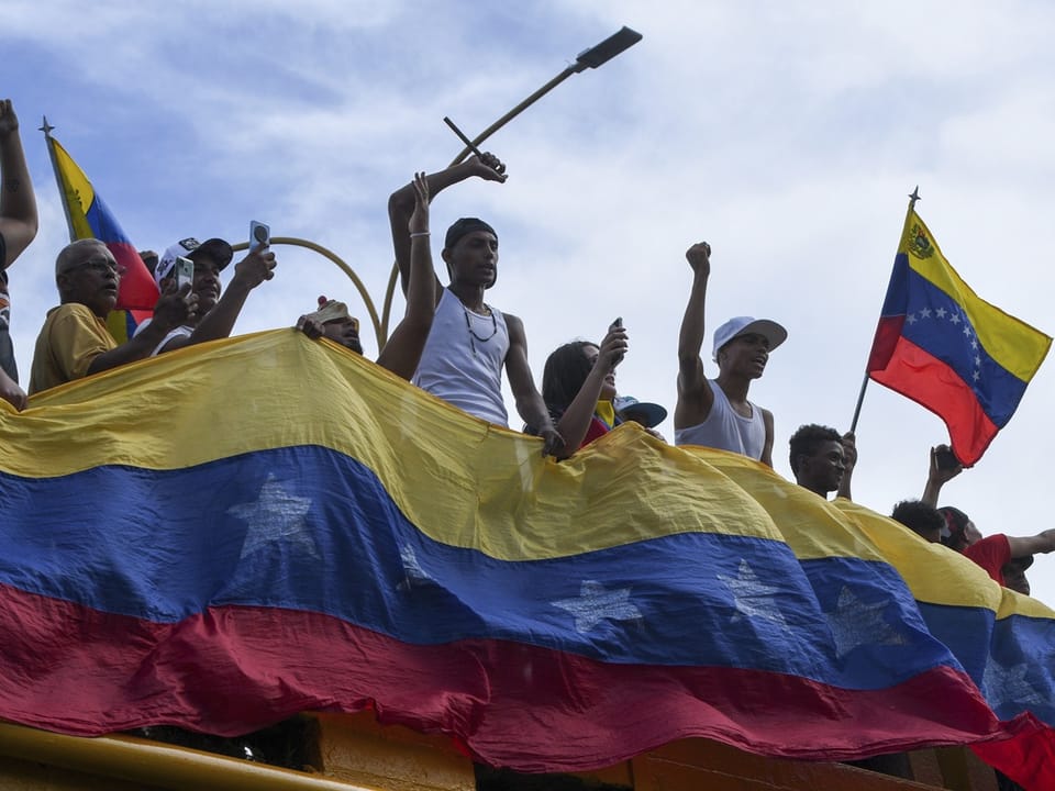 Menschen mit venezolanischer Flagge und erhobenen Fäusten.
