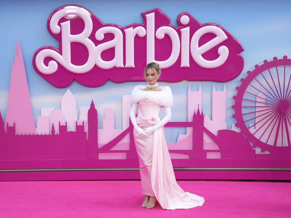 Margot Robbie posiert vor Barbie-Schriftzug auf dem roten Teppich.