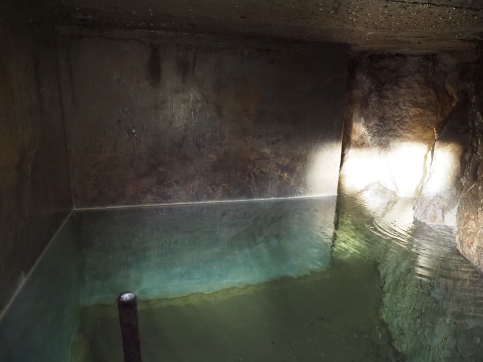Auf dem Bild ist das innere eines Quellbeckens zu sehen, das bis zur Hälfte mit Wasser gefüllt ist.