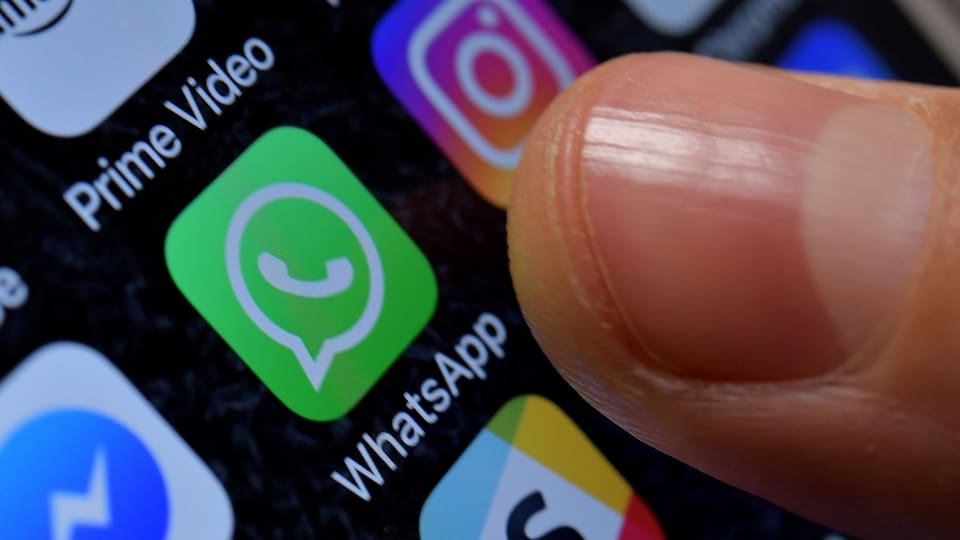 Ein Finger weist auf das WhatsApp-Symbol auf einem Bildschirm.