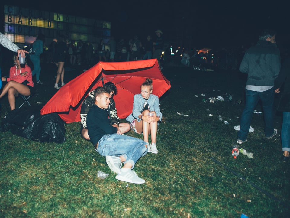 Festivalbesucher unter einem roten Sonnenschirm