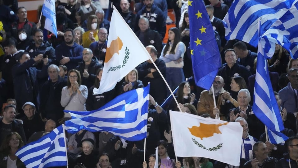 Leute klatschen, sie schwenken Fahnen von EU und Zypern.