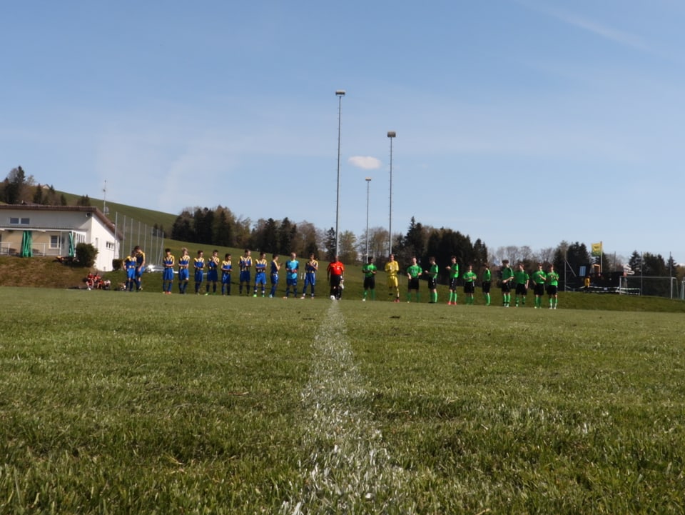 zwei Fussball-Mannschaften stellen sich auf der Mittelline auf