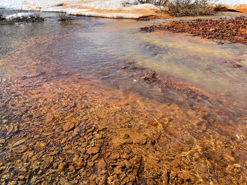 Ein Sediment mit orange-Färbung an einem Fluss.