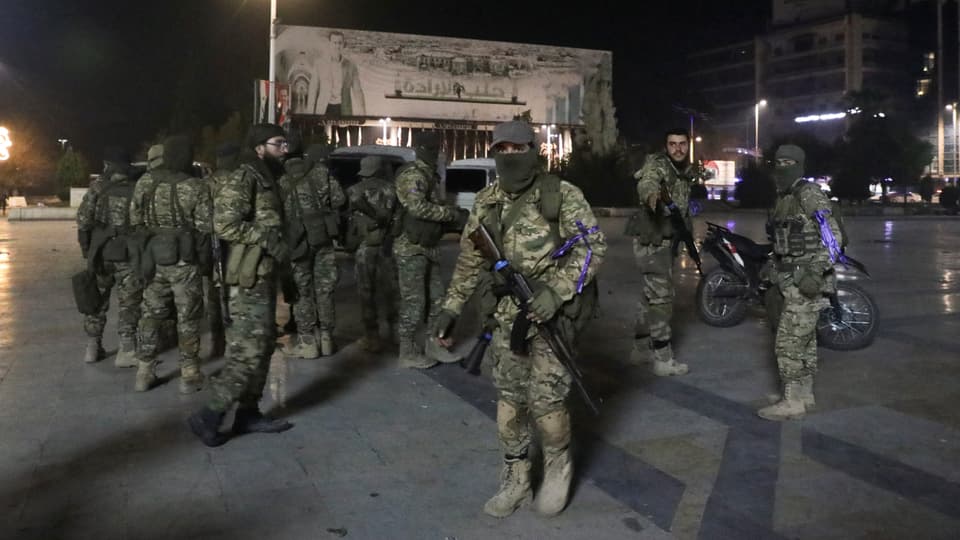 Militärische Einheit in Tarnkleidung versammelt auf Platz bei Nacht.