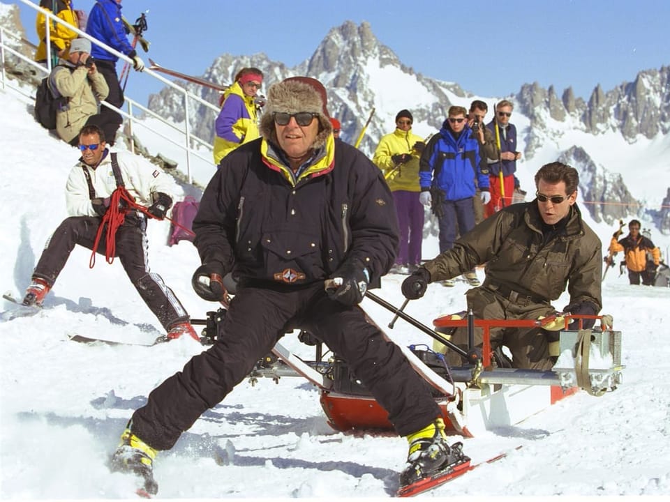 Mann auf Skiern wird auf einem Schlitten im Schnee gezogen.