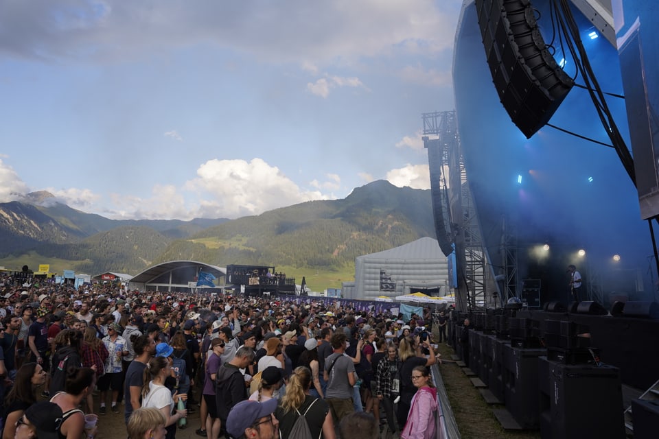 Das Publikum vor der Bühne und dahinter die Bergkulisse um das Festival.