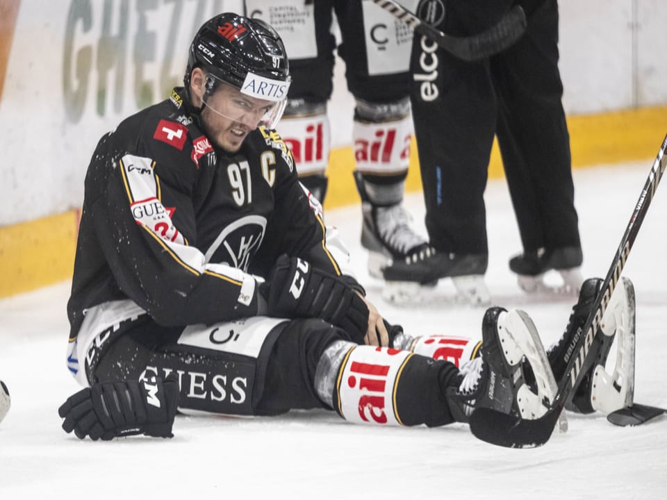 Eishockeyspieler sitzt auf dem Eis und scheint verletzt.