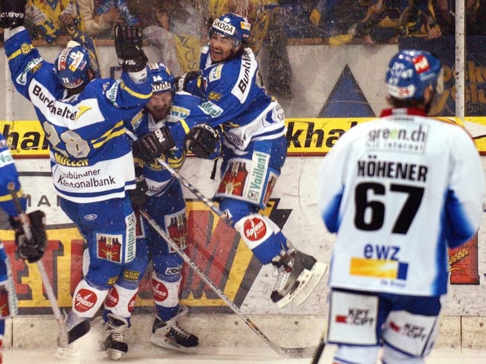 Eishockeyspieler in blauen Trikots feiern auf dem Eis.