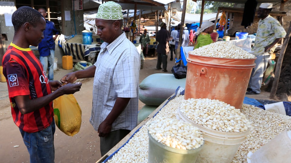 Ein Mann kauft einem Veräufer Mais ab.