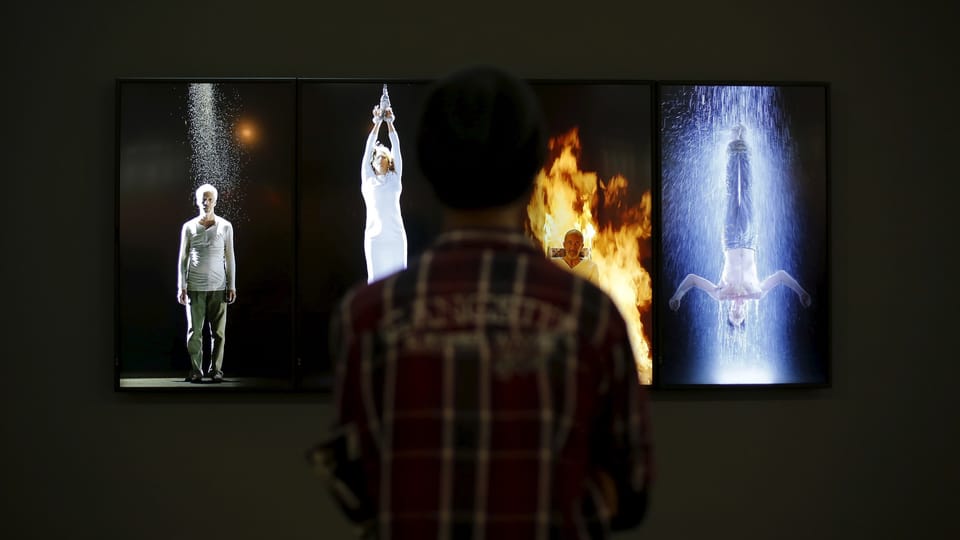 Person betrachtet Kunstinstallation mit vier Bildschirmen.