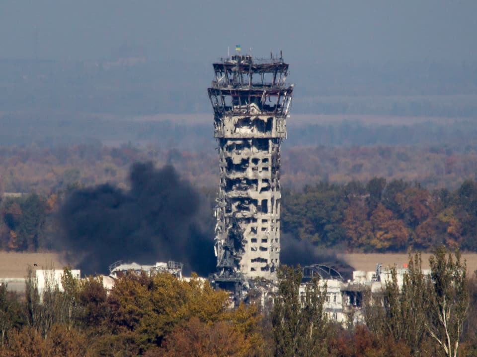 Ein aufrecht stehender, aber komplett zerschossener Flughafen-Turm.