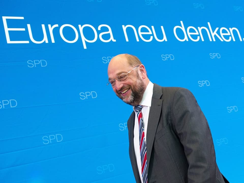 Schulz vor blauem Hintergrund.